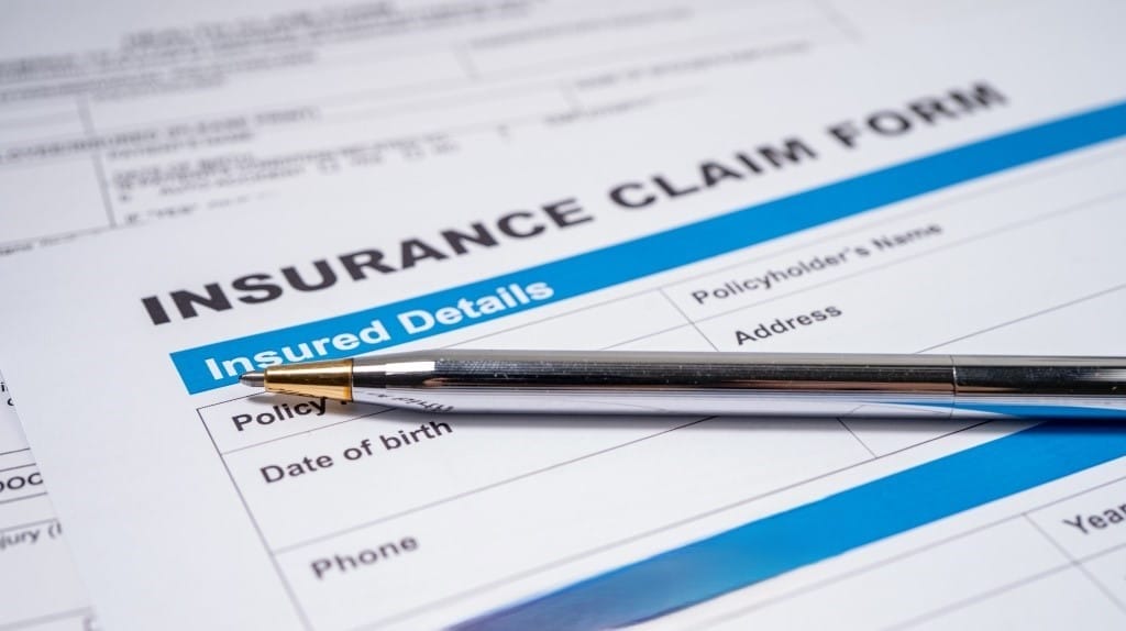A pen rests on an insurance claim form, highlighting the process of navigating insurance claims for unattended death cleanup.